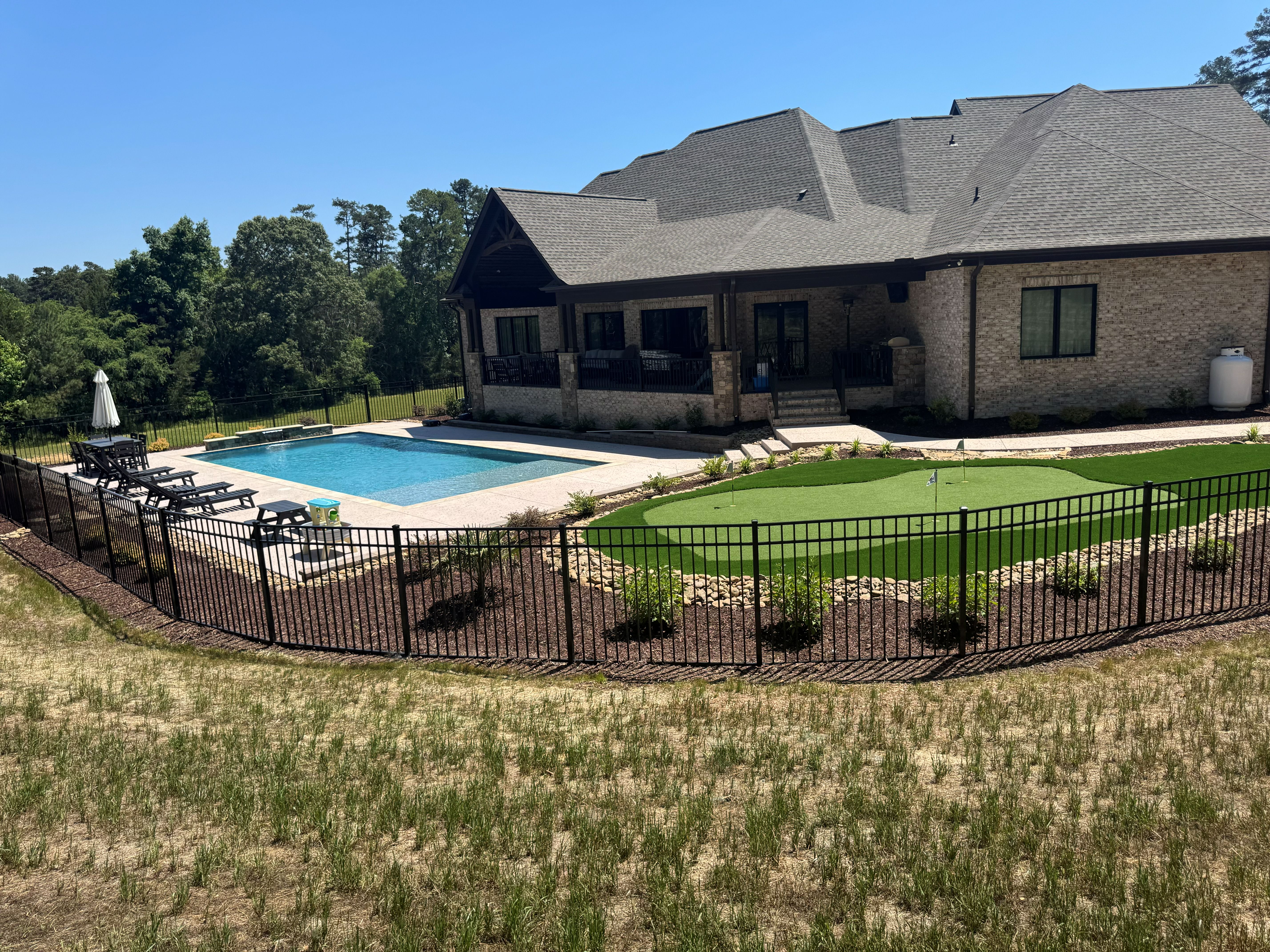 Rectangular pool with putting green and landscaping