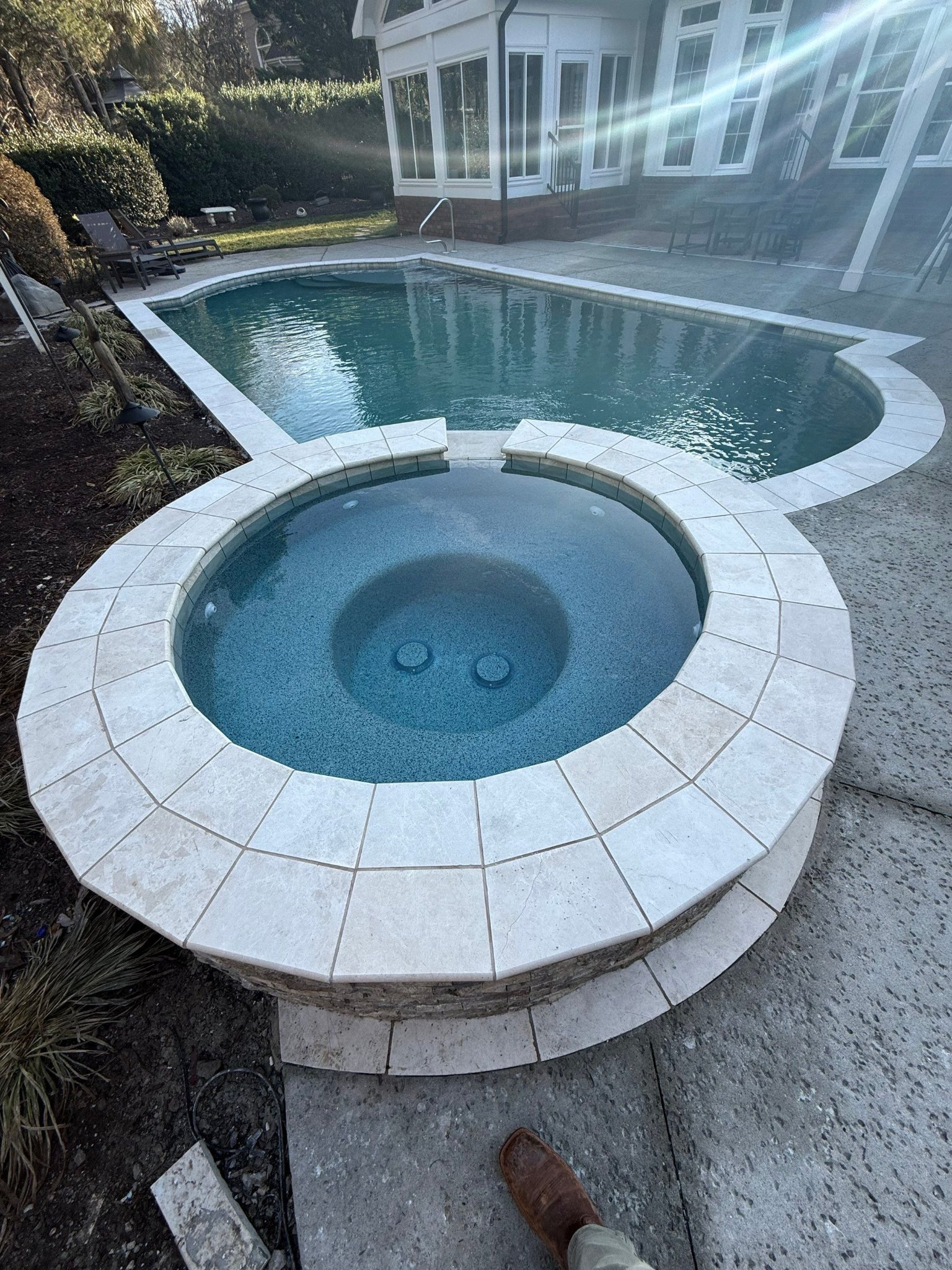 Custom concrete spa with travertine tile and freeform pool