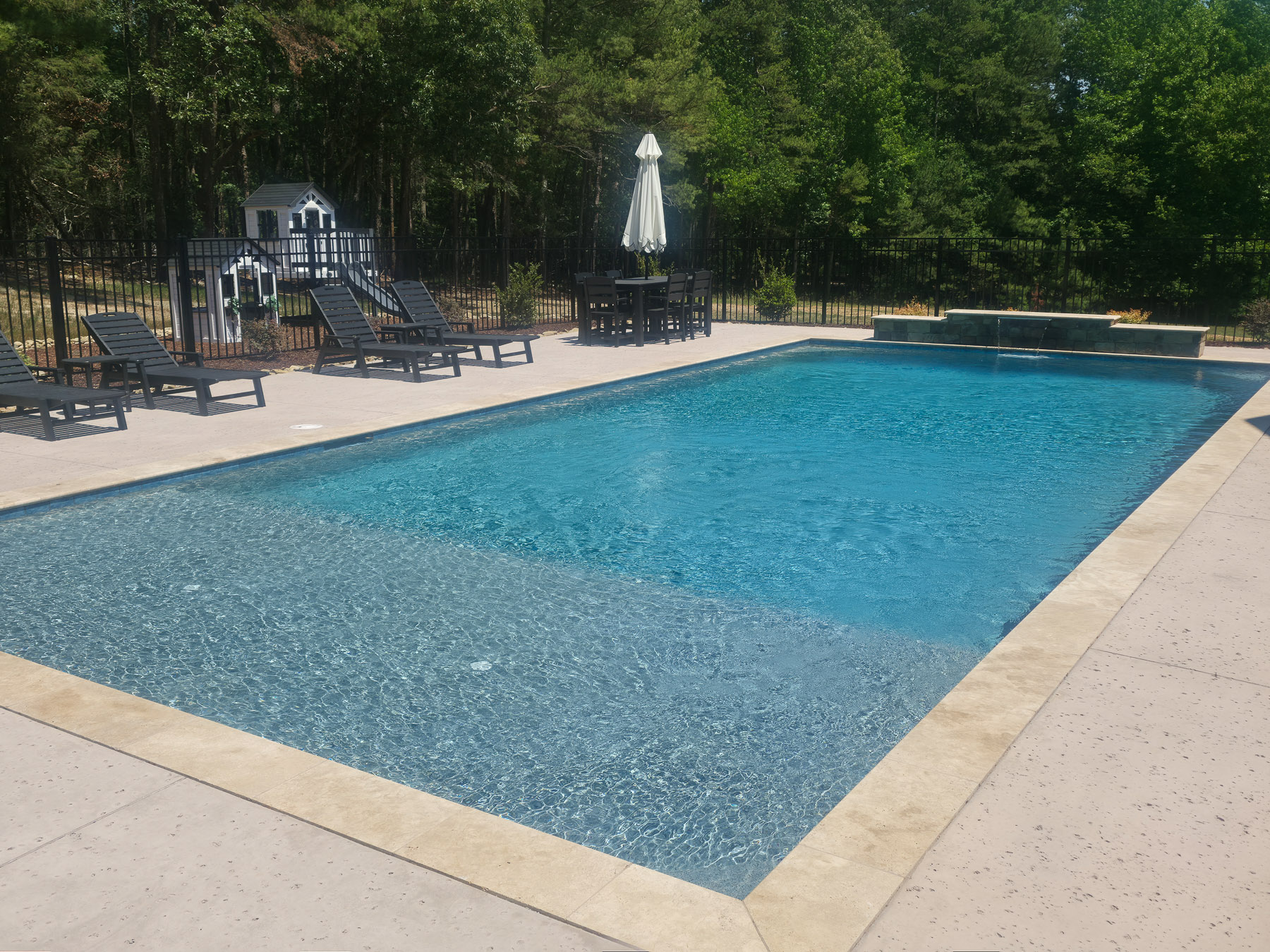 Rectangular concrete pool with travertine coping and raised spa