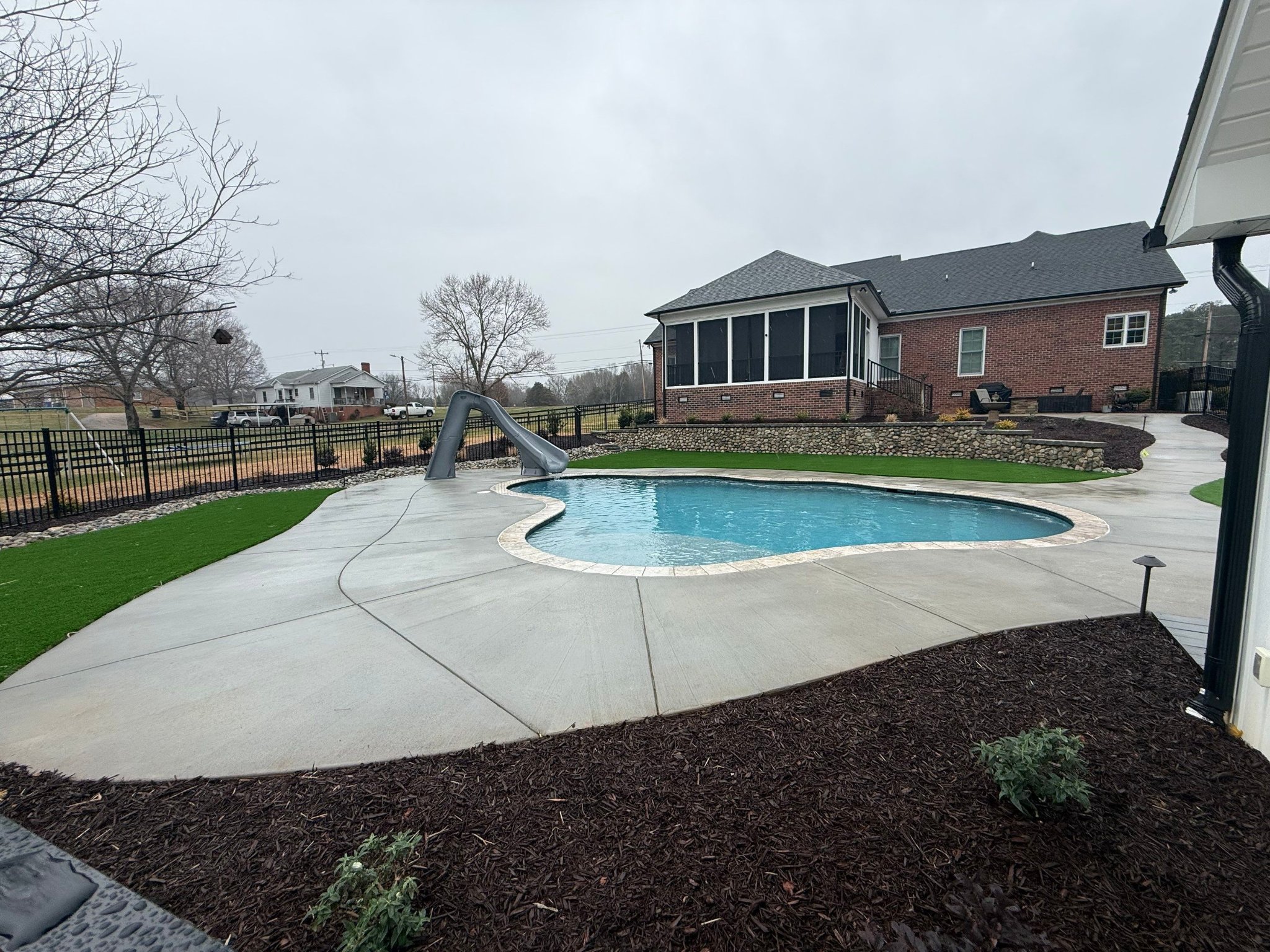 Custom pool with slide and concrete surround