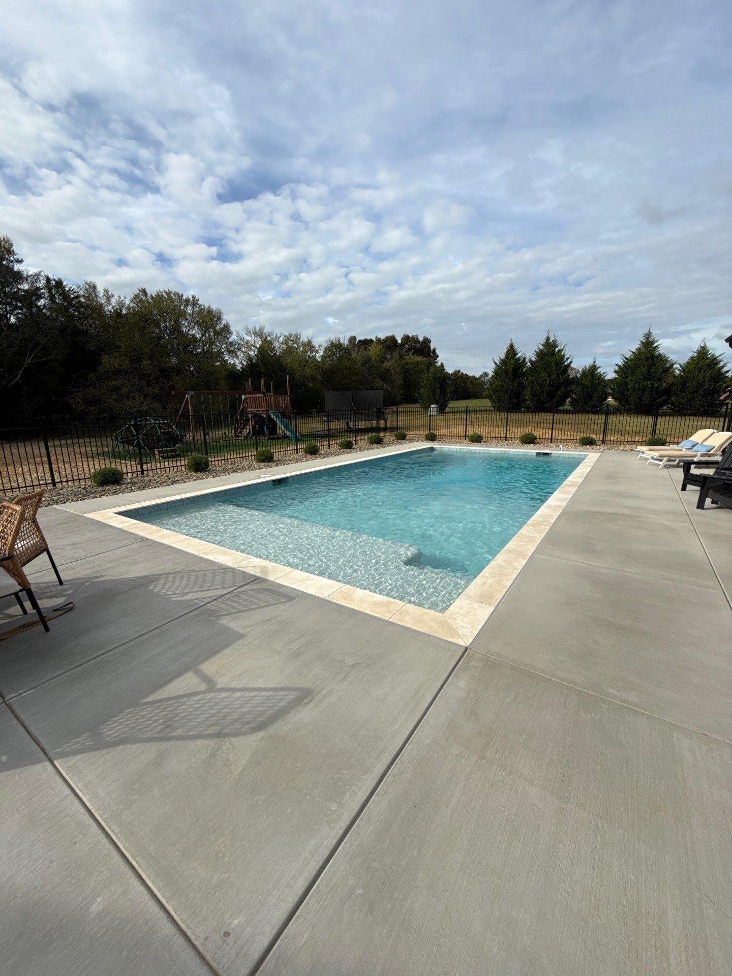 Completed concrete pool with travertine coping and concrete decking
